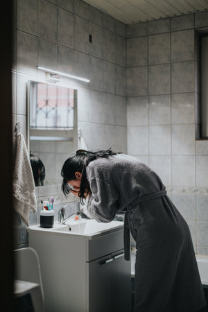 Person washing their face in a bathroom decorated with modern amenitiesの写真素材