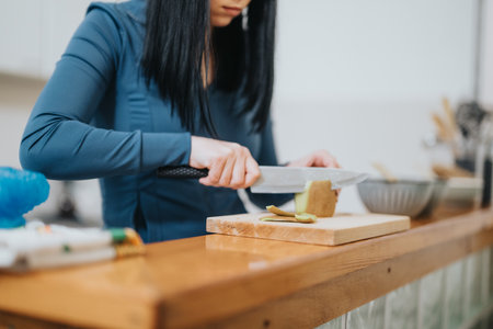 Woman slicing fruits on a wooden board in a modern kitchenの写真素材