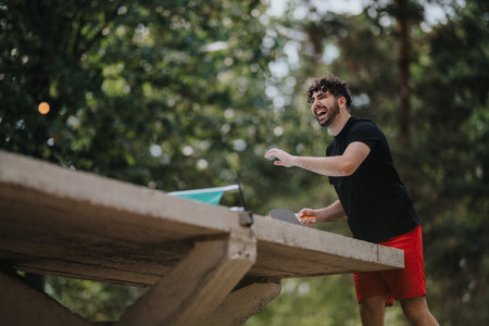 Young man playing outdoor sport on a raised concrete ledge, smiling and enjoying a playful momentの写真素材