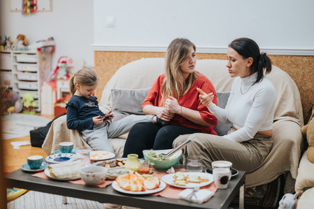 Two women talking while a child is playing during a casual gatheringの写真素材