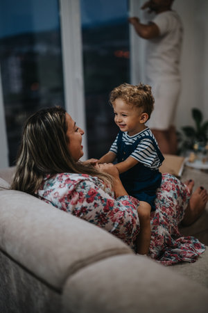 A loving mom and her happy son share a playful moment on the sofa at homeの写真素材