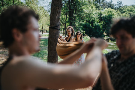 Friends enjoy a playful moment in the park as a swing is shared among themの写真素材