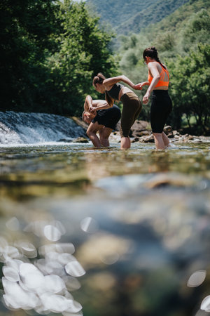 Friends wading in a shallow river surrounded by lush forest and natureの写真素材