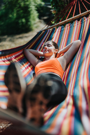 Young woman relaxing in a colorful hammock on a sunny outdoor dayの写真素材