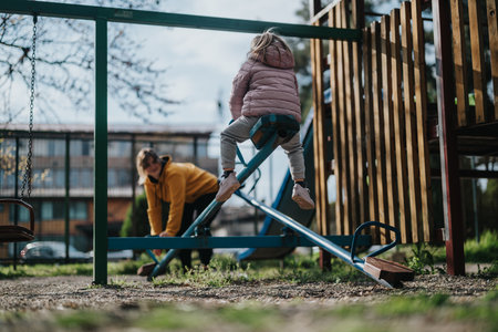 Mother and daughter in a playground enjoying seesaw activityの写真素材