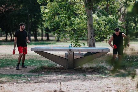 Two men play outdoor table tennis in a park on a unique concrete table surface