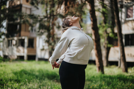 Woman Stretching Outdoors in a Hoodie on a Sunny Dayの写真素材