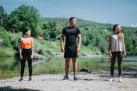 Group of friends practicing yoga by the riverside on a sunny dayの写真素材