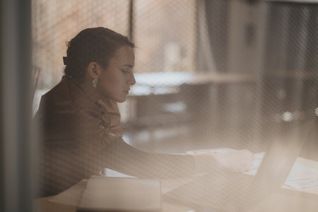 Woman working at desk focused on tasks in calm office environmentの写真素材