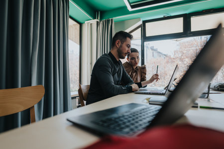Two colleagues collaborating on a project in a modern office environmentの写真素材