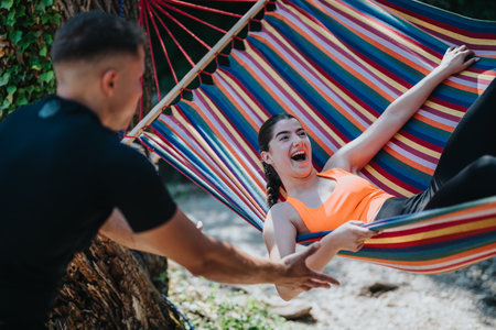 Friends Playing and Laughing Together on a Colorful Hammock Outdoorsの写真素材