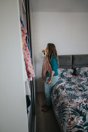Woman in a bedroom closet getting dressed in pajamas and robe for a cozy morning routineの写真素材