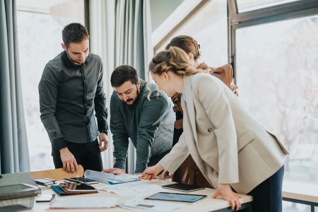 Team collaborating on project documents in a modern bright office settingの写真素材