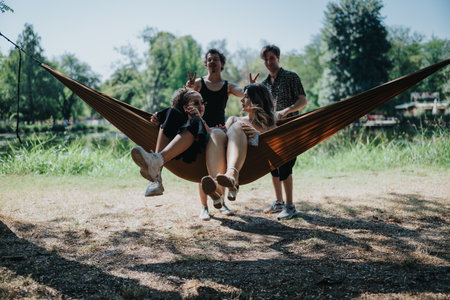 Friends relax in a hammock at the park, sharing laughs, sunshine, and carefree momentsの写真素材