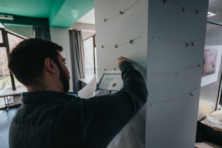 Person working on a creative display board with strings and clips in room