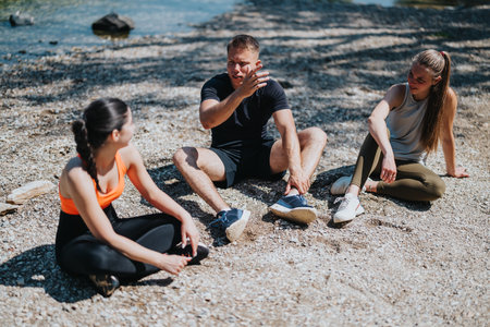 Three friends talking and relaxing near a river in active wearの写真素材
