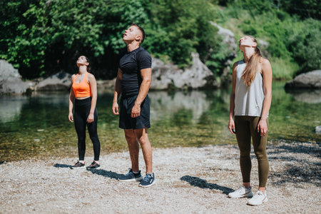 Group practicing mindfulness exercises by a serene riverside outdoorsの写真素材