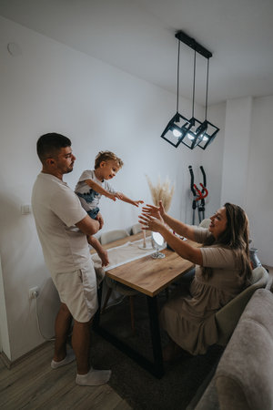Family at the dining table sharing a playful moment as toddler reaches for mom and dadの写真素材