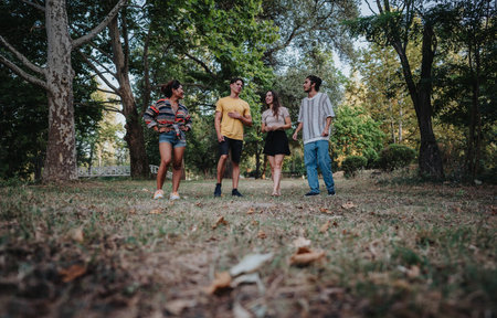 Friends share a casual chat in a sunlit park among trees and nature during a mellow afternoonの写真素材