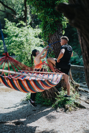 Couple Adjusting Colorful Hammock Outdoors in a Forested Settingの写真素材