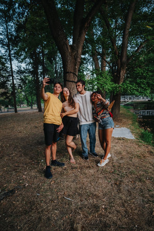 Friends Take a Selfie in the Park Under a Large Tree by the Lakeの写真素材