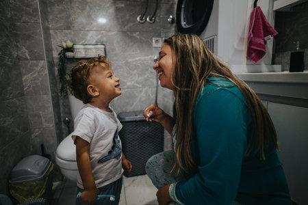 Mother smiles at toddler in the bathroom, sharing a playful moment and strong family bondの写真素材