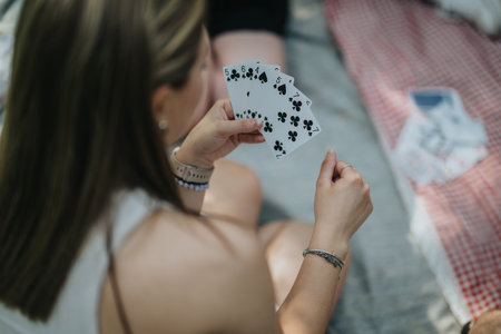 Woman playing cards outdoors during a sunny day in a park gatheringの写真素材