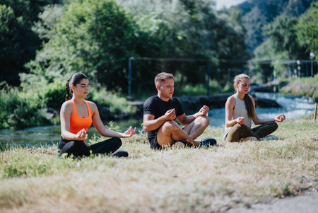 Group meditating together on a riverbank in a serene, outdoor settingの写真素材