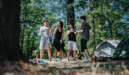 Friends enjoy a camping trip in the woods with tents, laughter, and sunny outdoor momentsの写真素材