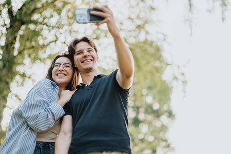 Young couple taking a cheerful selfie outdoors in a park settingの写真素材