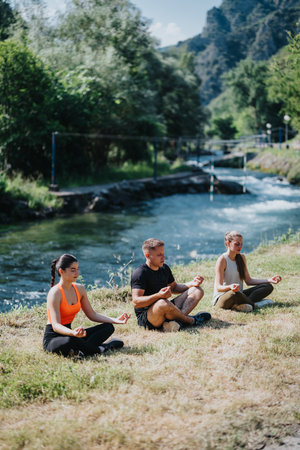 Group meditation practice near a serene river in a natural settingの写真素材