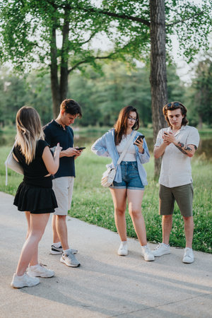 Group of friends using smartphones together in a serene park settingの写真素材