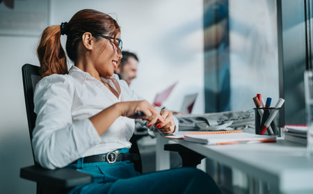 Busy office worker smiling at desk with notebook and pens in modern coworking space todayの写真素材