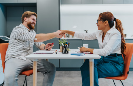 Business partners shake hands across a table in a modern office after a meeting