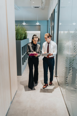 Multicultural business professionals discuss documents in modern office hallway