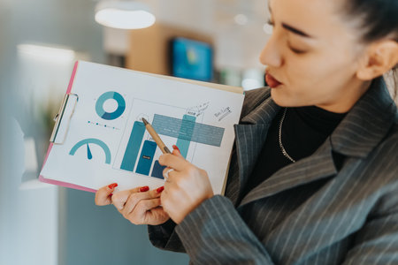 Business presentation in the office: woman presenting charts and graphs on a clipboardの写真素材