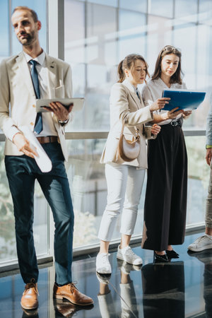 Business professionals review documents in a modern office lobby, discussing ideas and collaborationの写真素材