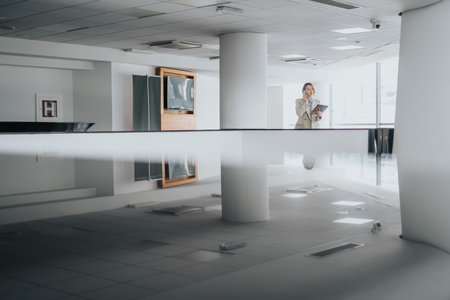 Professional woman on the phone in a bright corporate lobby with modern interior designの写真素材