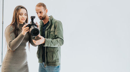 Man and woman reviewing camera features in a bright minimal spaceの写真素材