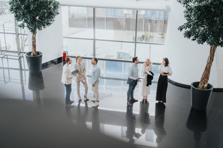 Professionals in a modern office lobby gather for a casual business meeting and networkingの写真素材