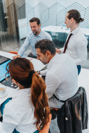 Multicultural business team collaborates in a modern office around a laptop during a meetingの写真素材