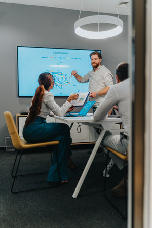 Team presents data in a modern office with a large screen and collaborative discussion