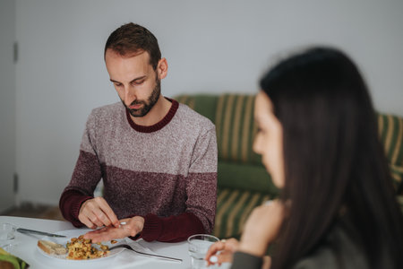 Man eating at table with another person in a cozy living roomの写真素材