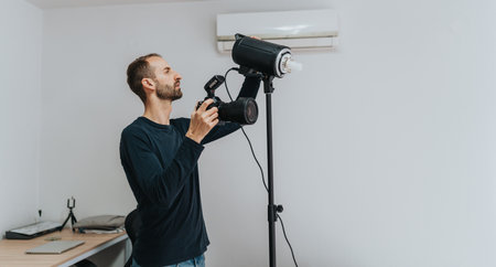 Portrait of a man adjusting a camera in a home studio setup.の写真素材