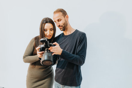 Two people reviewing camera settings together in a bright studio environmentの写真素材