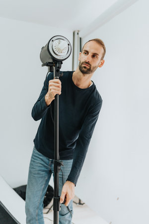 Man adjusting a studio light in a bright photography settingの写真素材