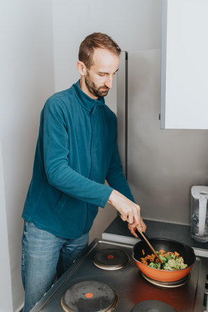 Man cooking vegetables in a saucepan on a modern kitchen stoveの写真素材