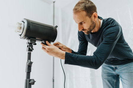 Man adjusting professional studio lighting in a creative workspace setup
