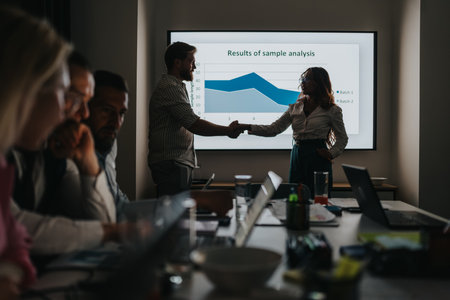 Business partners handshake after presentation during a team meeting with charted results in a conference roomの写真素材