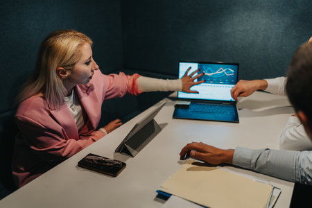 Business meeting with charts on laptop and collaborative discussion in a modern office